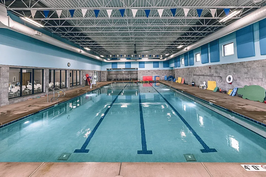 View of four-lane swimming pool surrounded by textured grey walls with blue trim and sound dampeners.