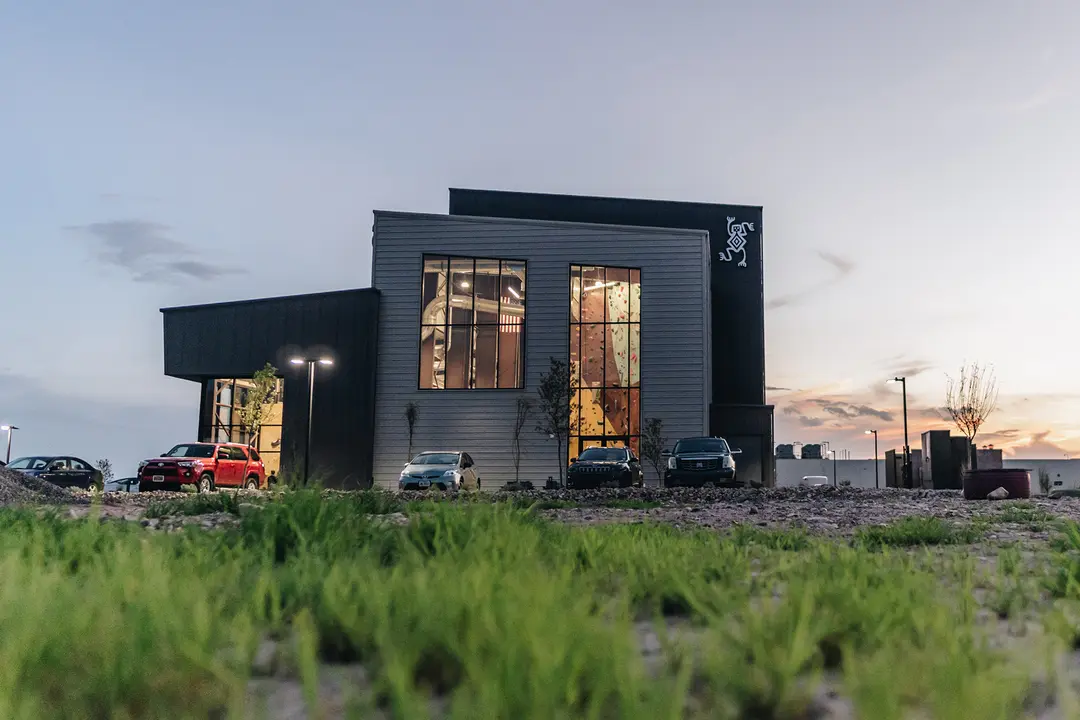 Sessions Climbing + Fitness building at sunset with tall windows and climbing walls visible inside.